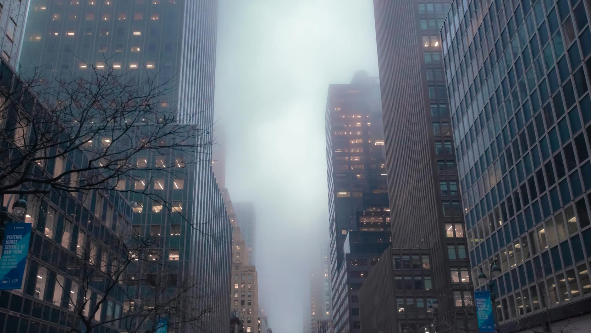 Skyscrapers shrouded in fog, captured in downtown New York City during the early morning.